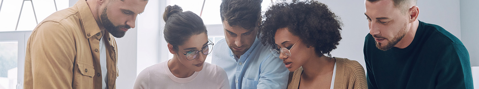 Young professionals working together on a project, all looking at paperwork together