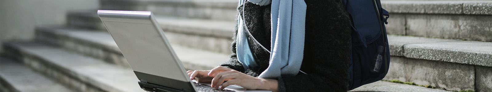 A college student using her laptop on the steps of campus