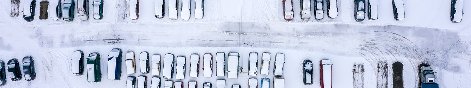 Fleet of vehicles in a snow covered parking lot during a snow storm and winter weather