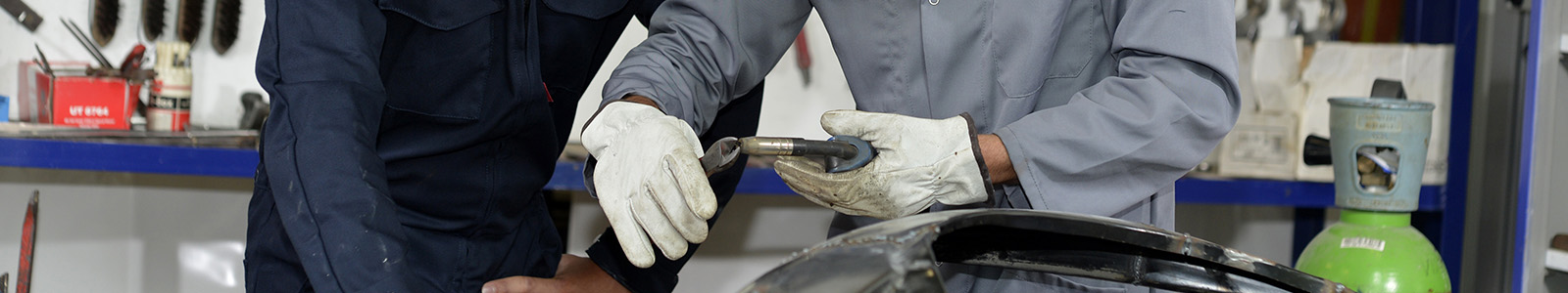 A student watches their teacher demonstrate welding safety and best practices