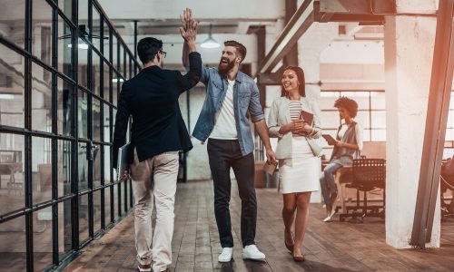 Happy employees in an office high five and celebrate